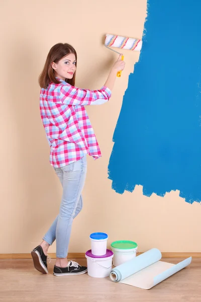 Beautiful woman paints wall