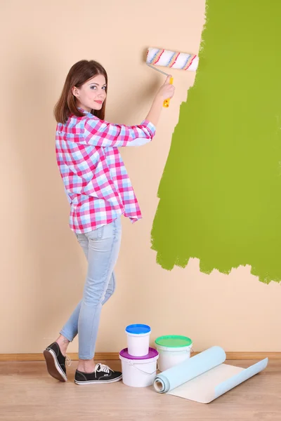 Beautiful woman paints wall