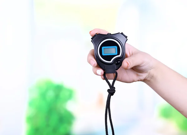 Electronic sport timer in  female hand on bright blurred background