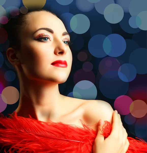 Beautiful woman with  red feather on bright background