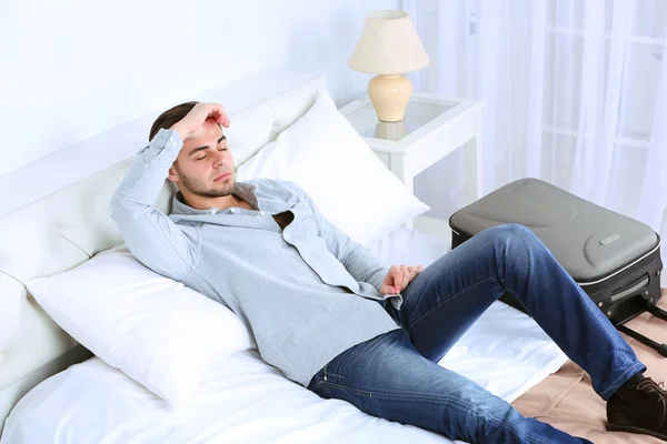 Tired man resting on bed in room