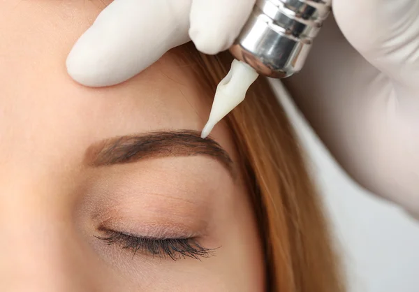 Cosmetologist making permanent makeup, close up