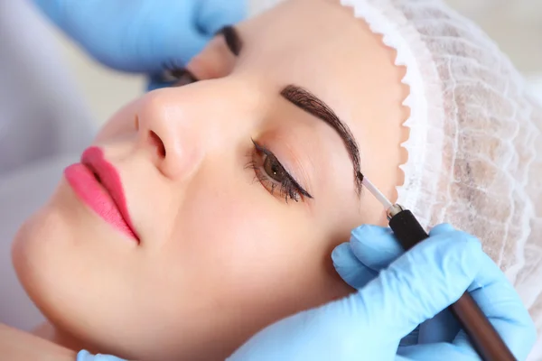 Cosmetologist applying permanent make up on eyebrows