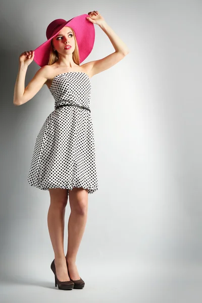 Expressive young model in pink hat on gray background