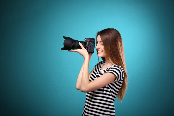 Young female photographer taking photos on blue background