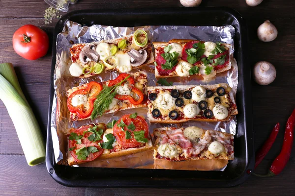 Different sandwiches with vegetables and cheese on pan on table close up