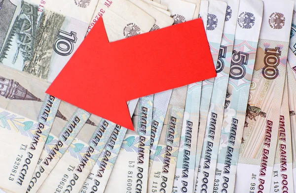 Red arrow on Russian money as depreciation of currency, closeup