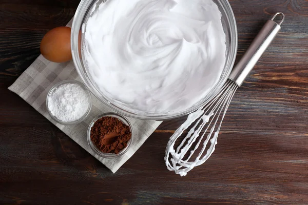 Whipped egg whites and other ingredients for cream on wooden table, top view