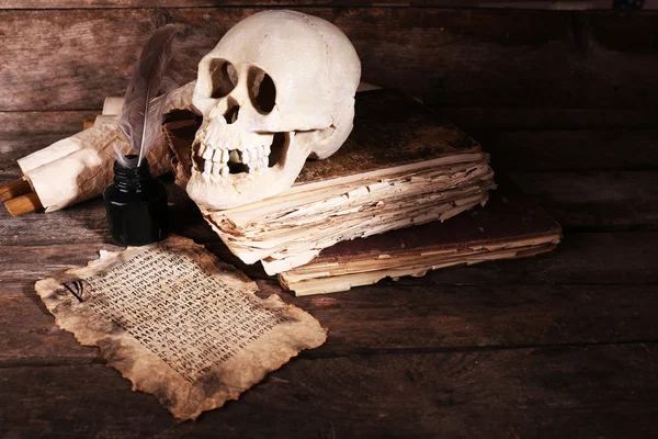 Human skull, retro book and quill