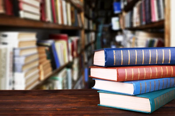 Stack of books on table on bookshelves background