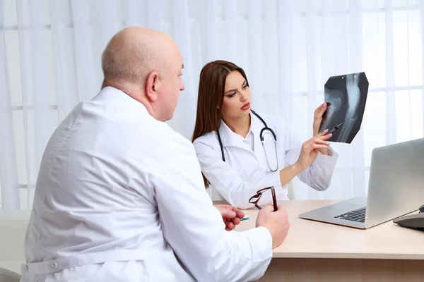 Doctors receiving X-ray results in office on white background