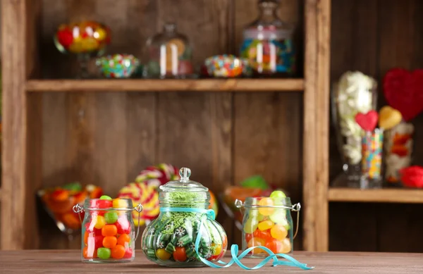 Colorful candies in jars on table in shop