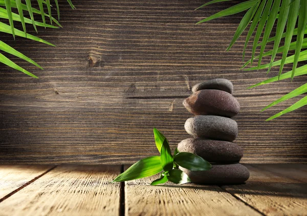 Spa stones with green leaves on wooden background