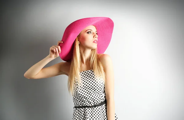 Expressive young model in pink hat on gray background