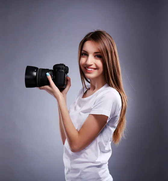 Young female photographer taking photos on grey background