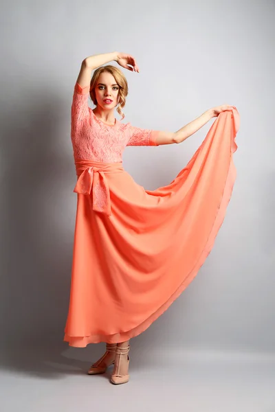 Beautiful young woman in color dress posing on light background