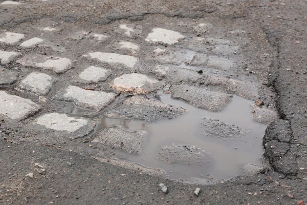 Very bad quality road with potholes and puddles