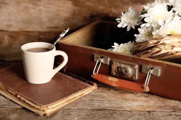 Old wooden suitcase with old books and flowers on wooden background