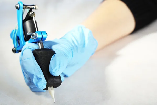 Tattoo machine in hand of Tattoo artist, close-up. on light background