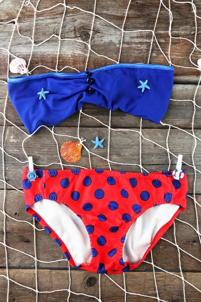 Sea still life with swimsuit on wooden table, top view