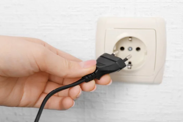 Hand putting plug in electricity socket close up