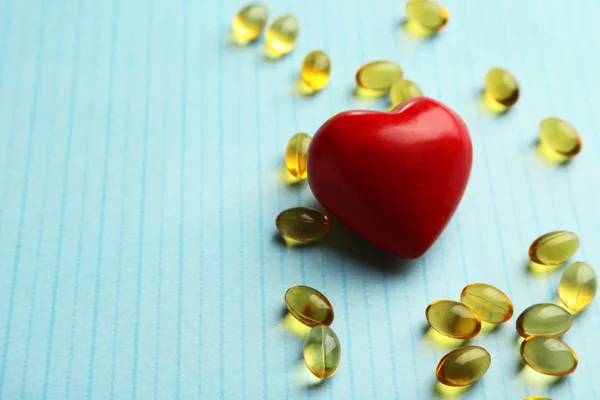 Red heart and cod liver oil, on blue background
