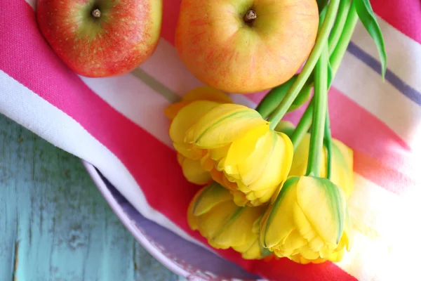 Beautiful bouquet of tulips with fruits on napkin close up