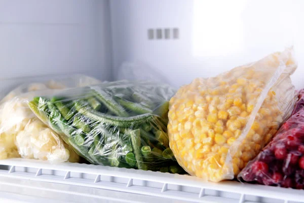 Frozen berries and vegetables in bags in freezer close up