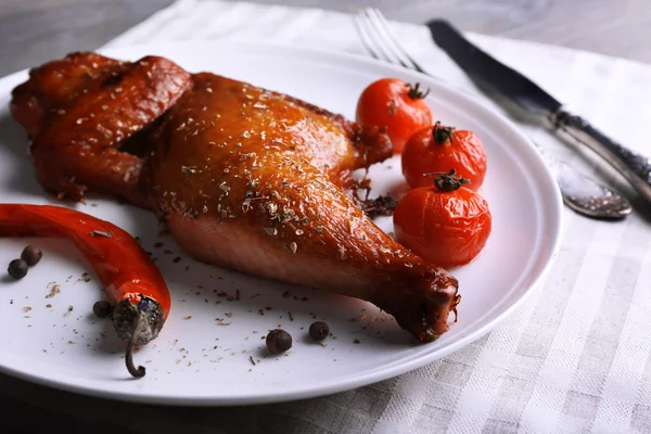 Smoked chicken leg  with vegetables on plate on table close up