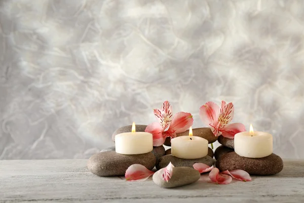 Still life with spa candles on light wallpaper background