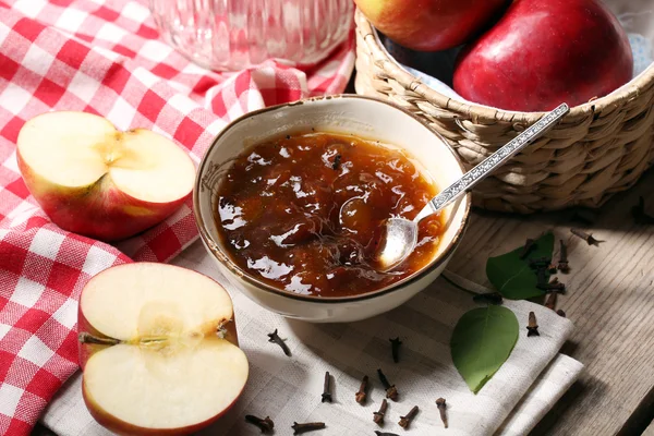 Apple jam and fresh red apples on wooden table close-up