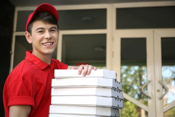 Young man delivering pizza box near house