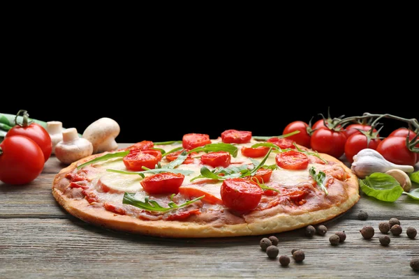 Delicious pizza with cheese and cherry tomatoes on wooden table on dark background