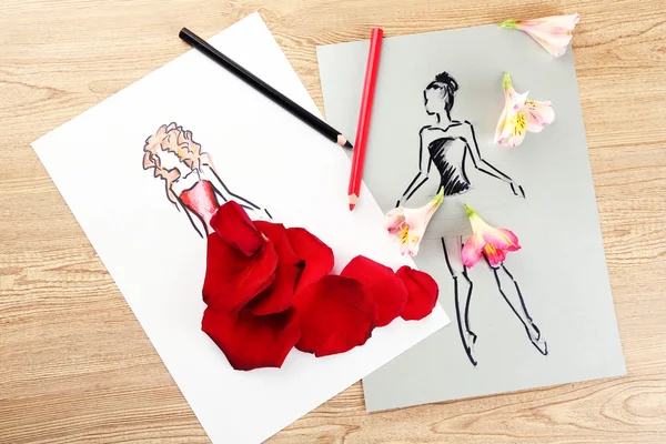 Pictures with flower petals and pencils on wooden table