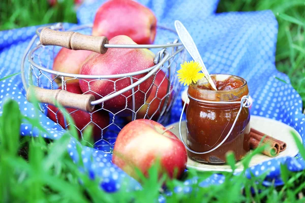 Apple jam in jar and fresh red apples outdoors