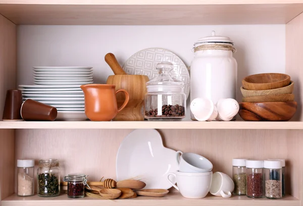 Kitchen utensils and tableware on wooden shelves