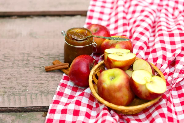 Apple jam in jar and fresh red apples outdoors