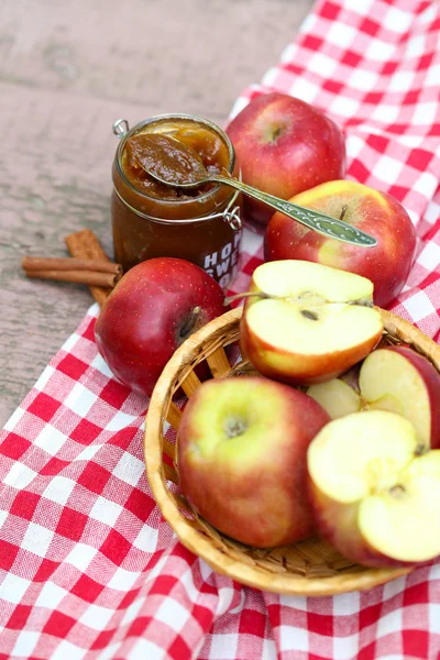 Apple jam in jar and fresh red apples outdoors