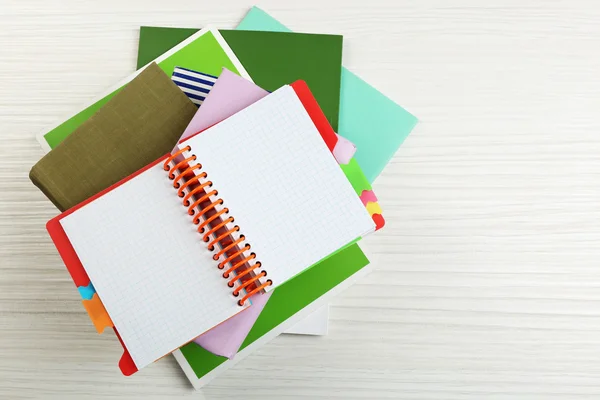 Notebook on top of pile of books and magazines on wooden background