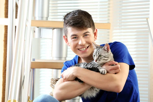 Handsome young man with cute cat sitting on steps at home