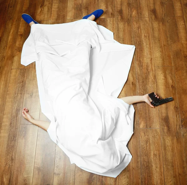 Crime scene simulation, young man lying with gun on floor