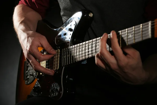 Young man playing on electric guitar