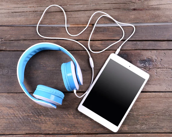 Headphones with tablet on wooden background