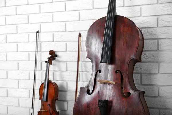 Cello and violin on bricks wall background