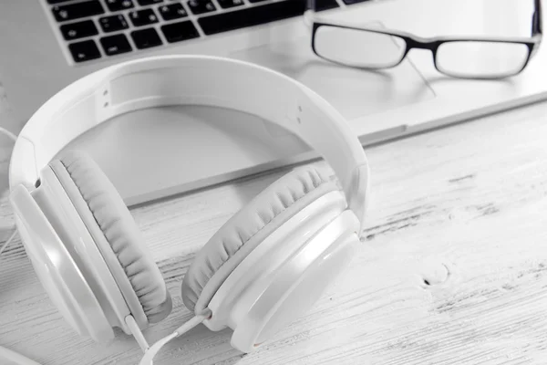 Headphones with laptop on table close up