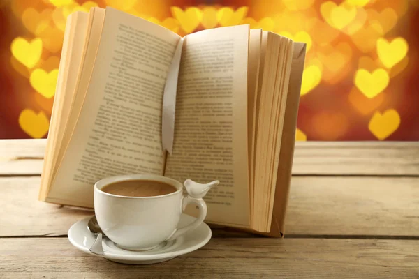 Cup of coffee with open book on bright background