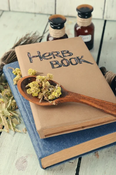 Dried herbs in wooden spoon on books
