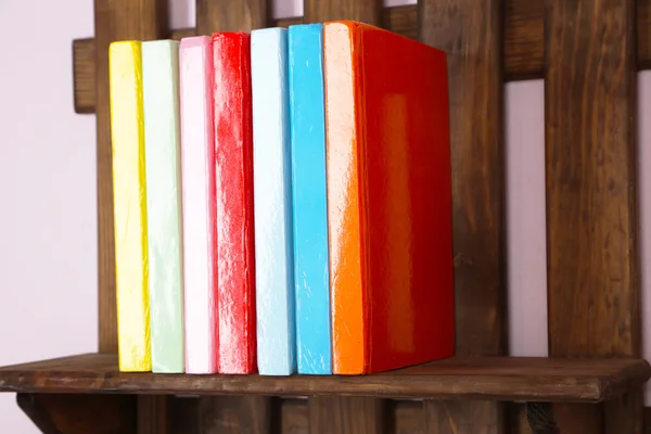 Wooden shelf with books on wall, closeup