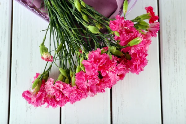 Beautiful bouquet of pink carnation on wooden table close up