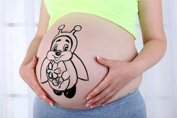 Body art on belly of pregnant woman on light background